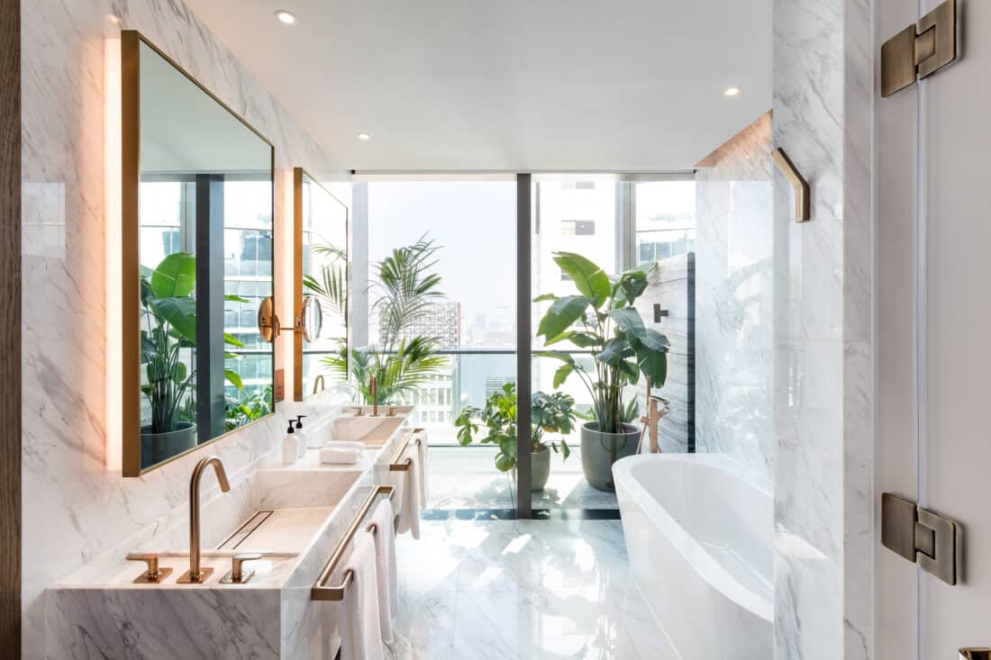 Copyright: Origin One Ltd. for AXOR / Hansgrohe SE. The Hari Suite’s bathroom showcases AXOR in Brushed Bronze, with AXOR Citterio M at the washbasin and a striking floor-standing AXOR Urquiola thermostat by the bath